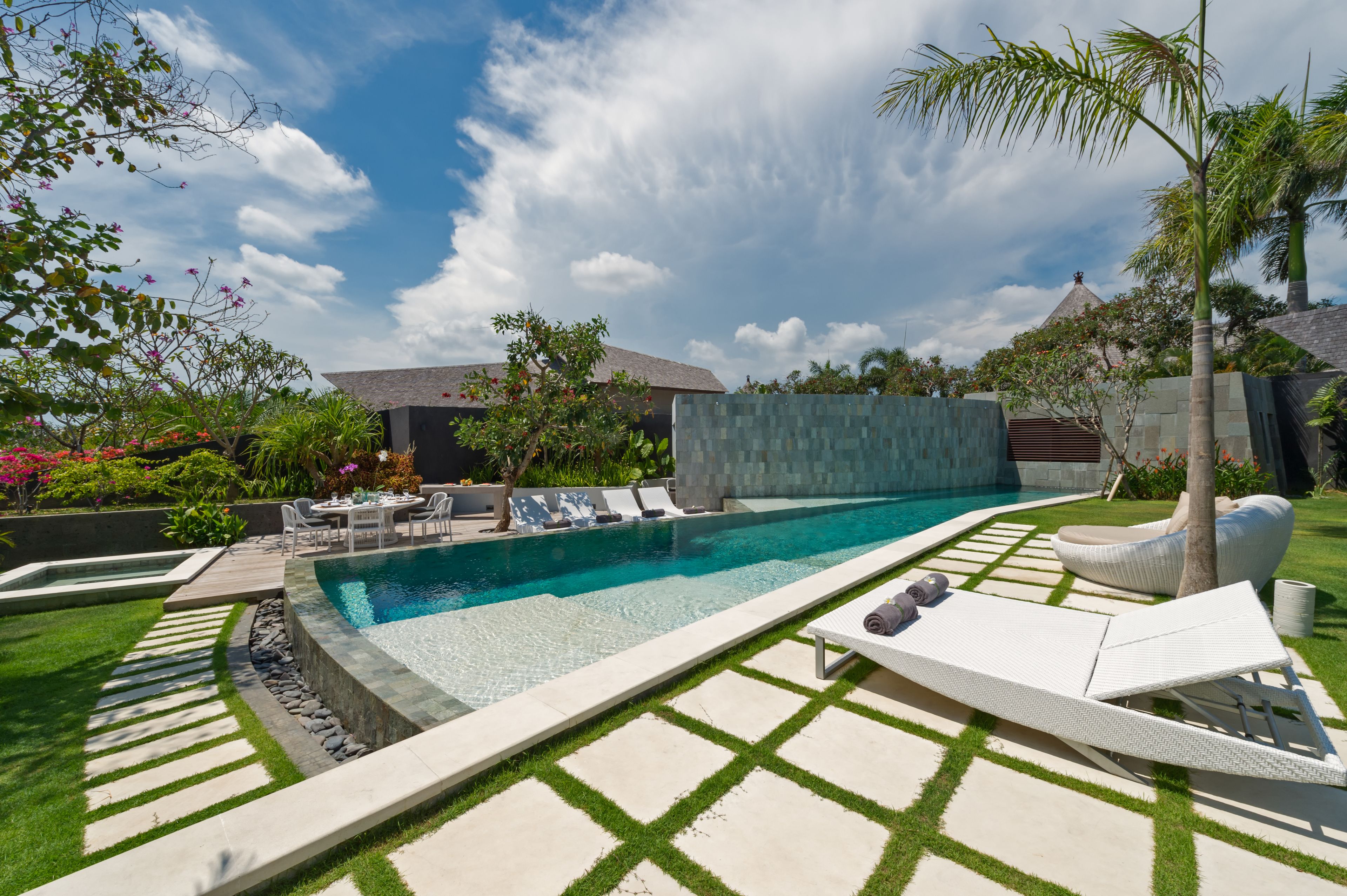 A swimming pool with lounge chairs and a table, surrounded by a well-maintained lawn and garden.