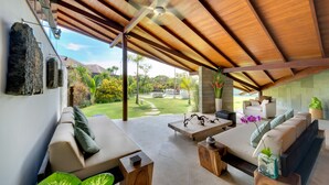 A spacious living area with a wooden ceiling, a sofa, a coffee table, and a view of a garden. - The Layar Designer Villas and Spa (Seminyak)