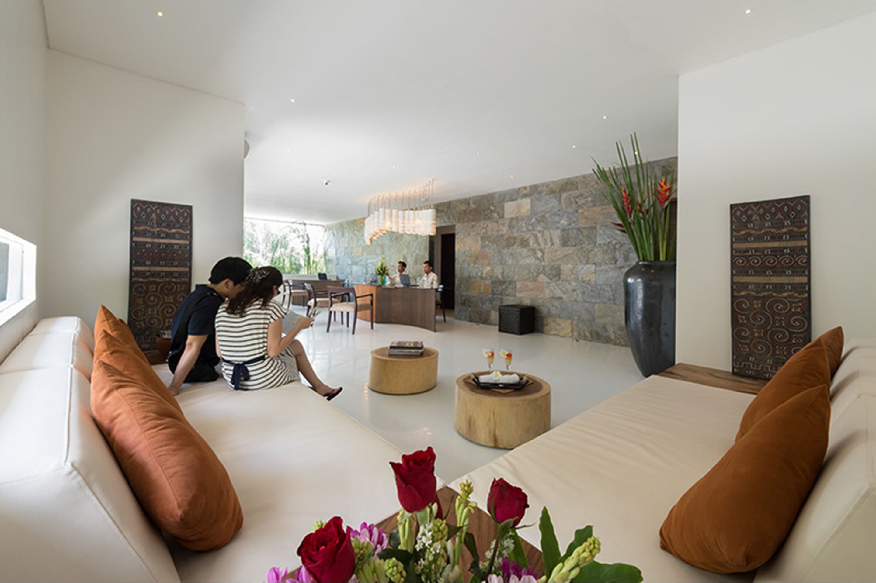 A modern hotel lobby with a reception desk, seating area, and decorative elements like vases and wall art.