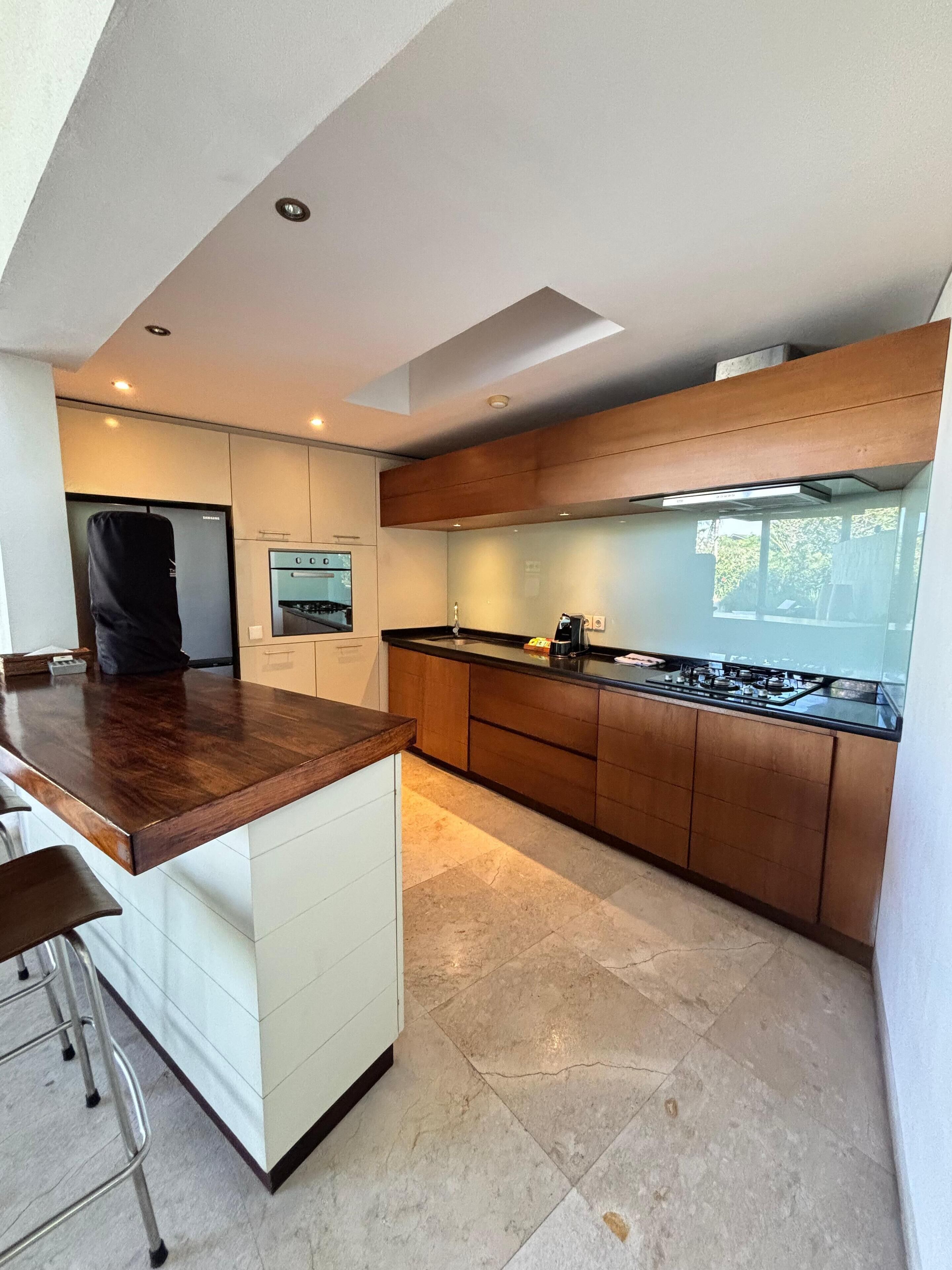 Una cocina moderna con encimera de madera, electrodomésticos integrados y una isla grande con taburetes de bar.