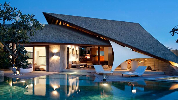 A modern house with a swimming pool, lounge chairs, and a well-lit interior. - The Layar Designer Villas and Spa (Seminyak)