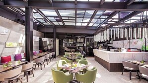 A modern restaurant with a central dining area, a bar, and a kitchen visible in the background. - The Layar Designer Villas and Spa (Seminyak)