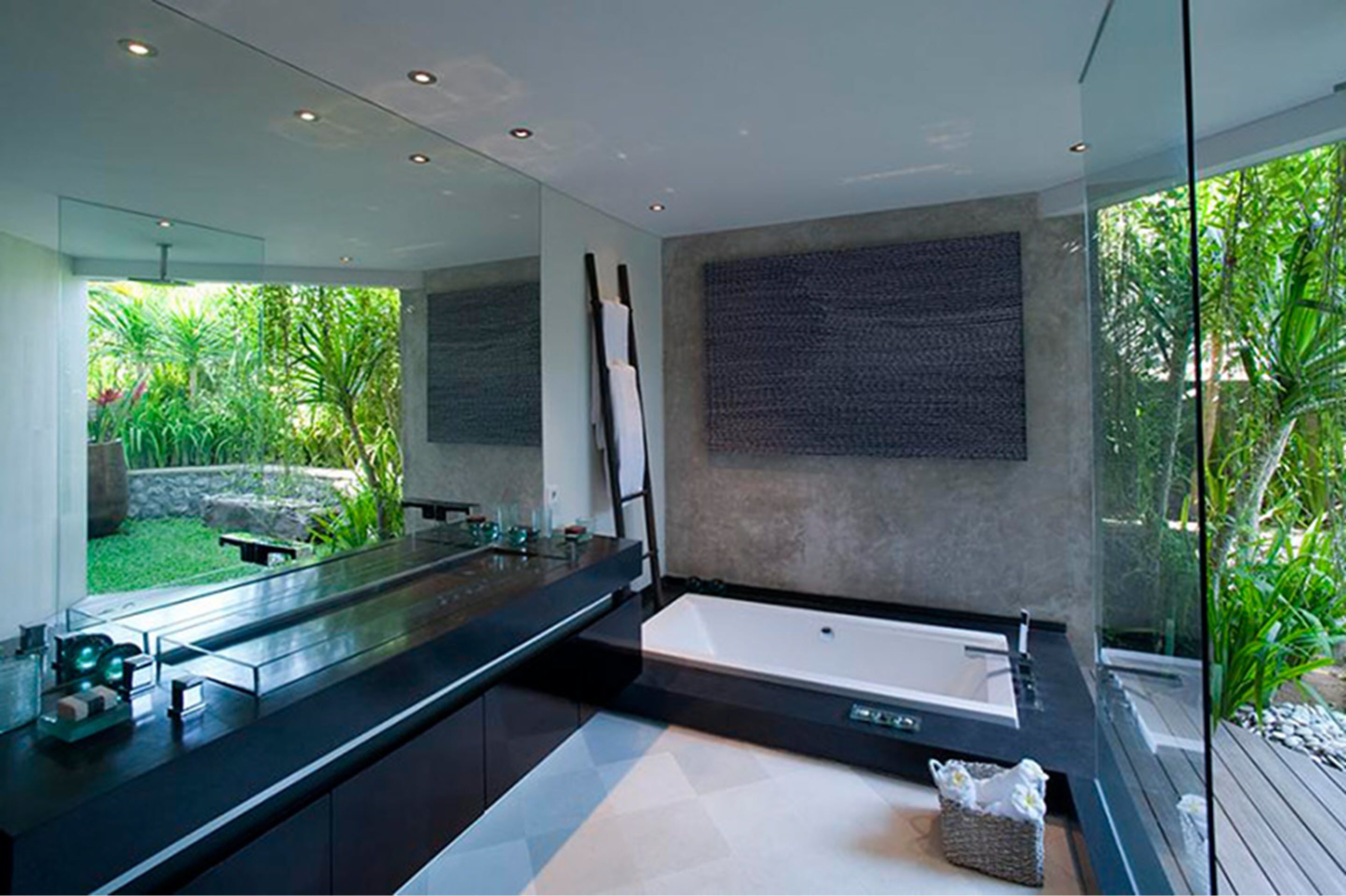 A modern bathroom with a large bathtub, a long countertop, and a large mirror.