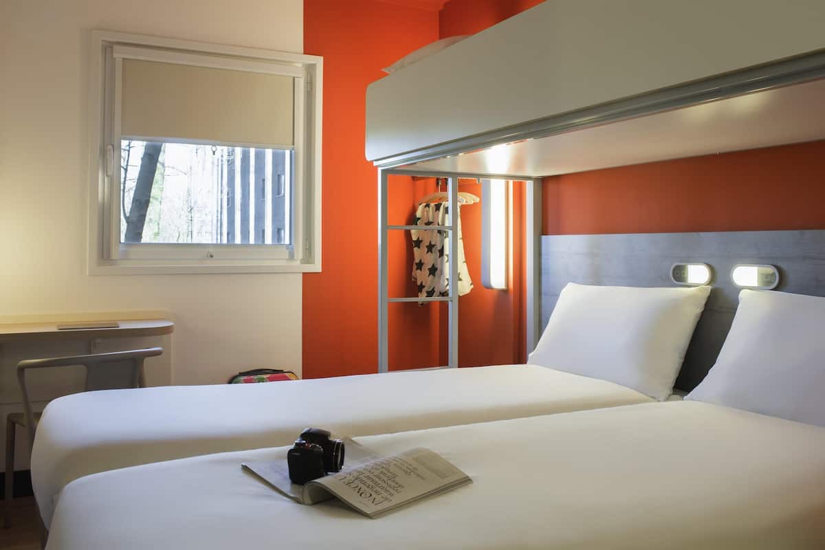 Ein Hotelzimmer mit zwei Betten, einem Schreibtisch und einem Fenster.