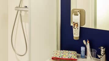 Un baño con ducha, espejo, lavabo y artículos de aseo.