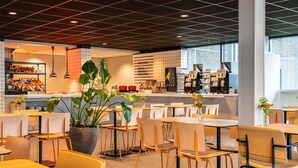 L'intérieur d'un café moderne, avec des tables et des chaises, un comptoir à café et une grande plante en pot.