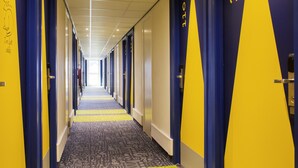Un couloir d’hôtel avec des portes numérotées de 110, agrémenté d’un tapis à motifs et de murs bleus et jaunes.