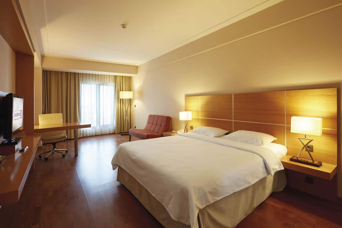 Una habitación de hotel con una cama grande, un escritorio con una silla, un televisor y una lámpara.