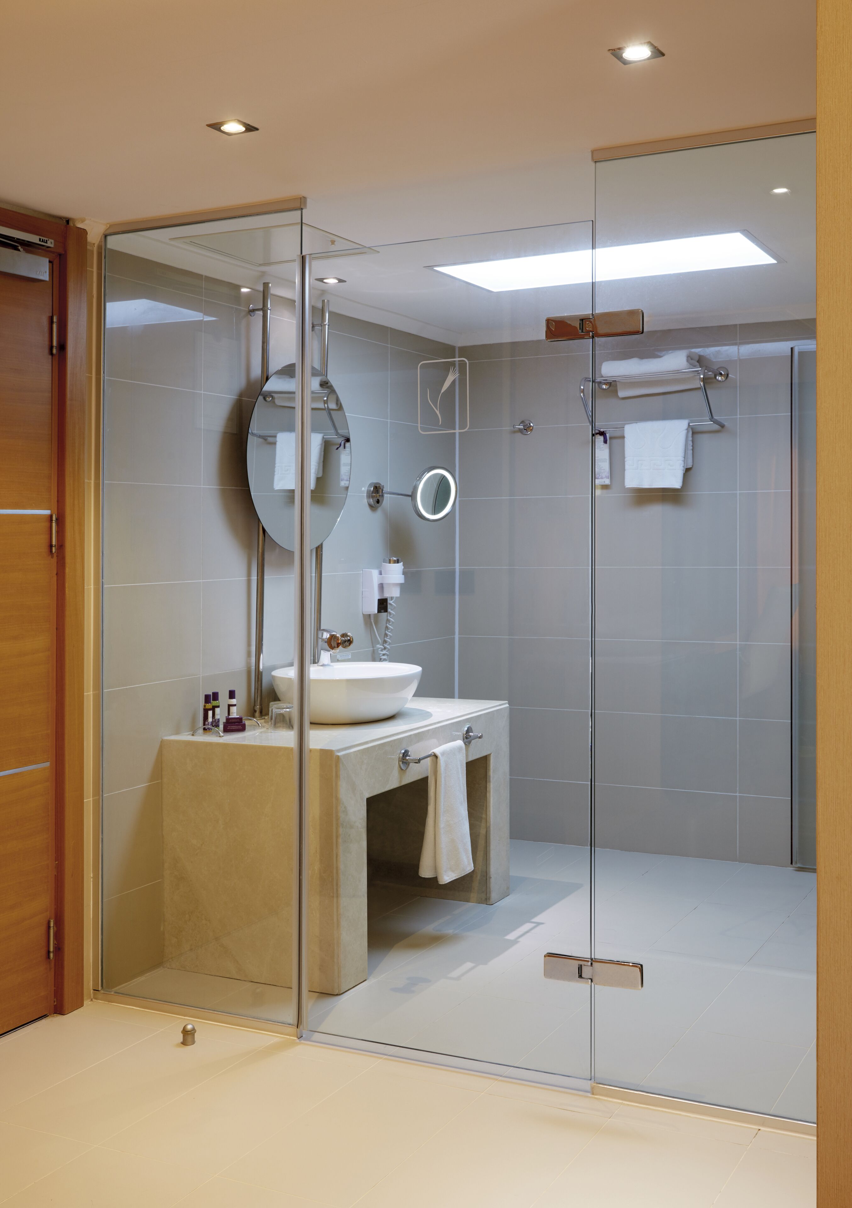 Un baño moderno con ducha envuelta en vidrio, un lavabo con espejo y un perchero para toallas.