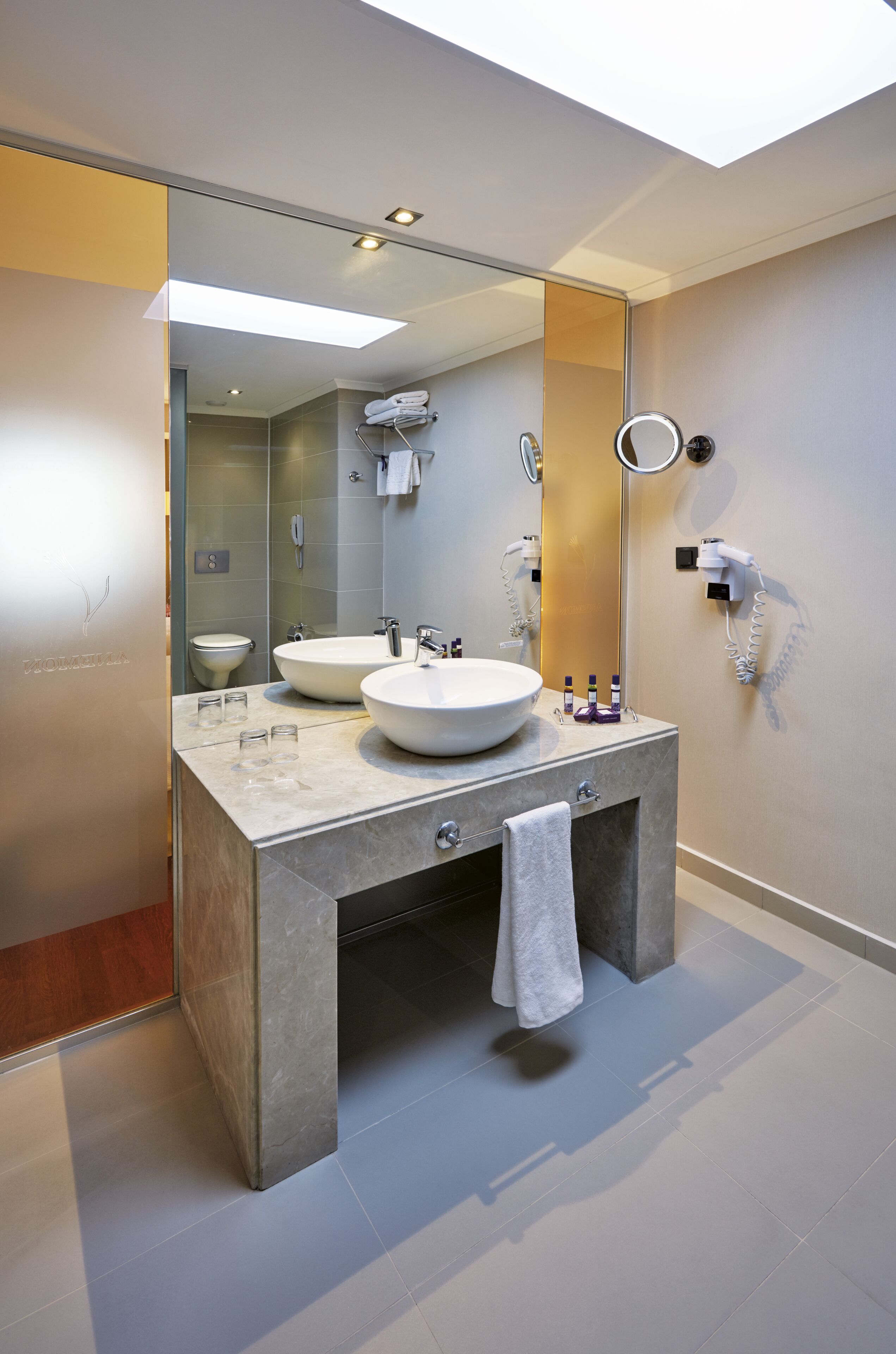 Ein modernes Badezimmer mit zwei Waschbecken, einem großen Spiegel und einem Föhn an der Wand.