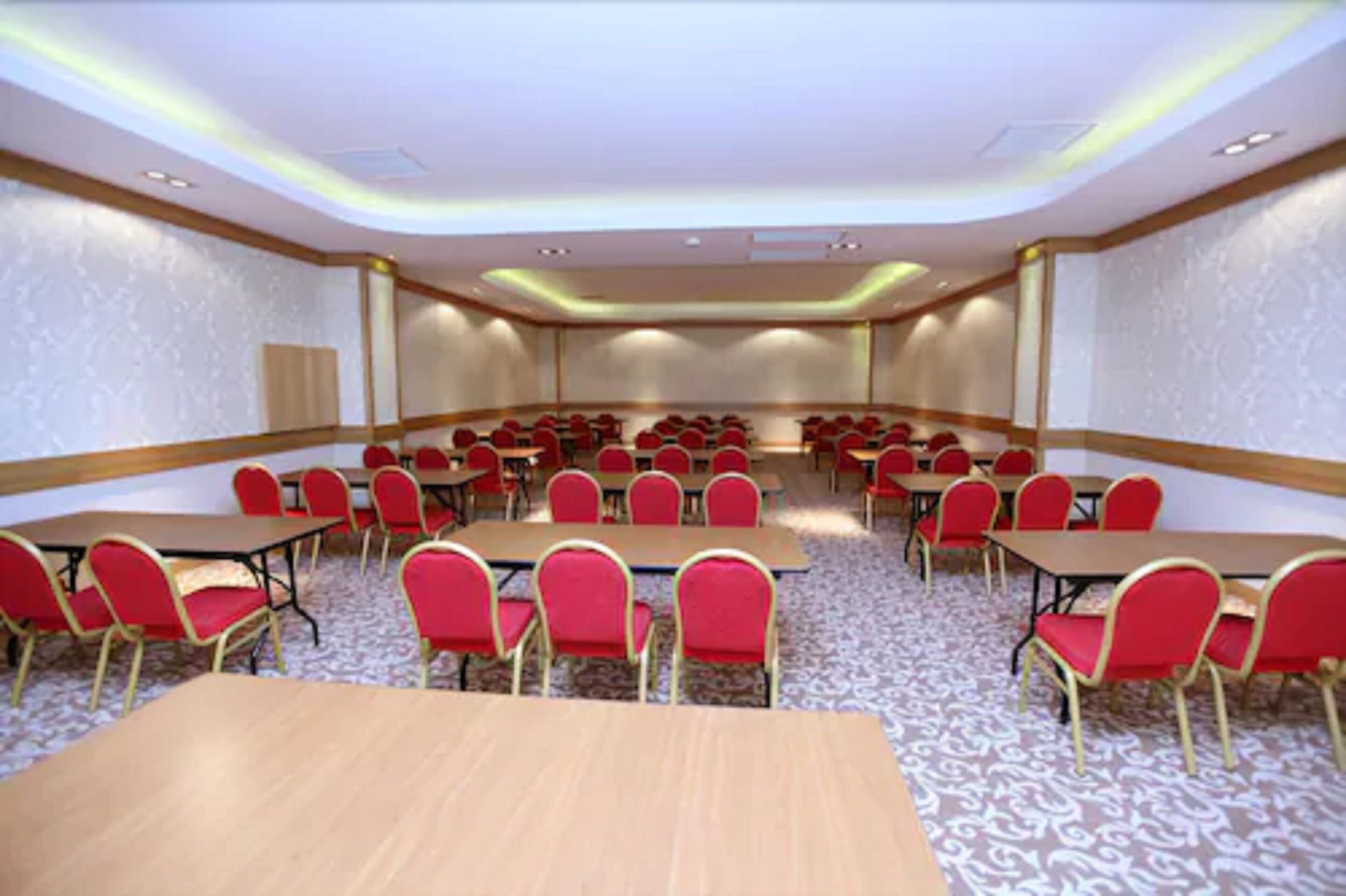 A conference room with multiple tables and chairs, carpeted floor, and a patterned wall design.
