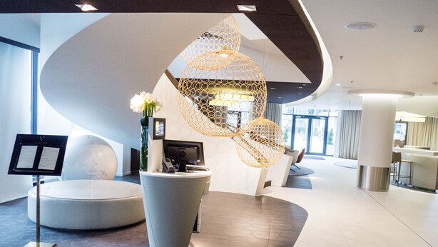A modern reception area with a globe, a reception desk, and a unique spherical light fixture. - Pullman Brussels Centre Midi (Brussels)