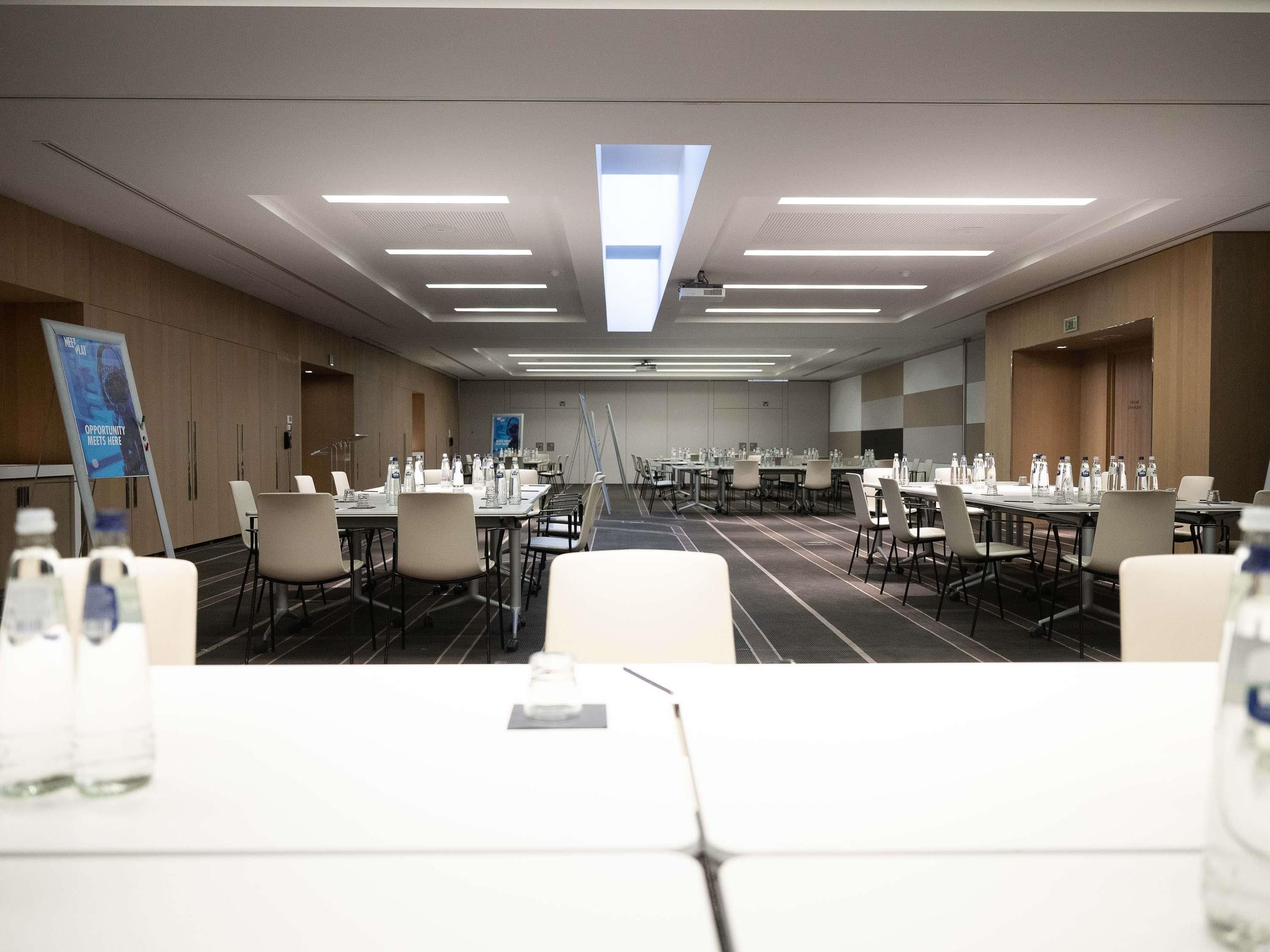 A conference room with multiple tables, chairs, and water bottles.