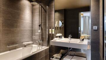 Un baño moderno con ducha de vidrio, un espejo grande y un tocador con lavamanos y toallero.