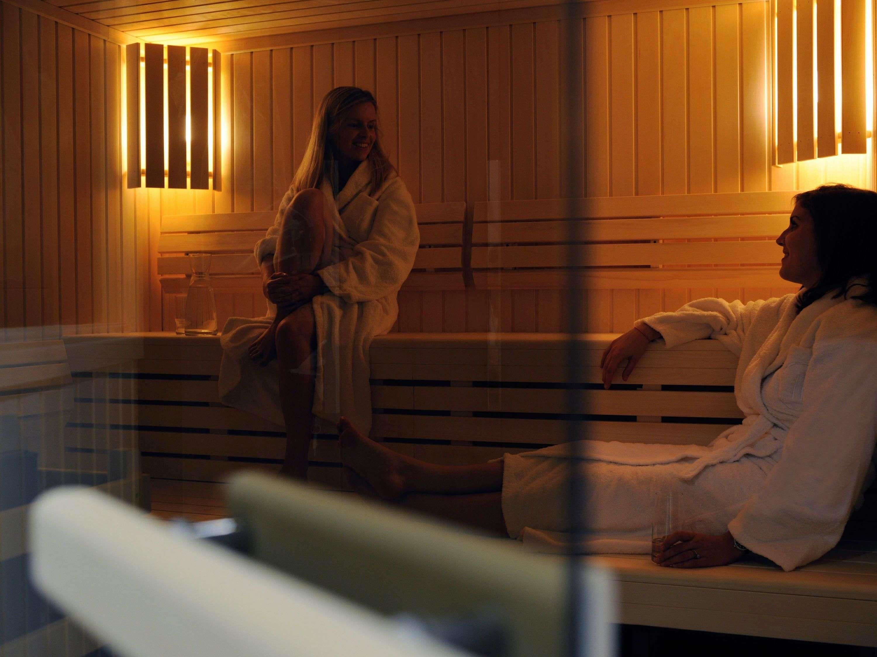 A sauna with wooden benches and wall-mounted lights.