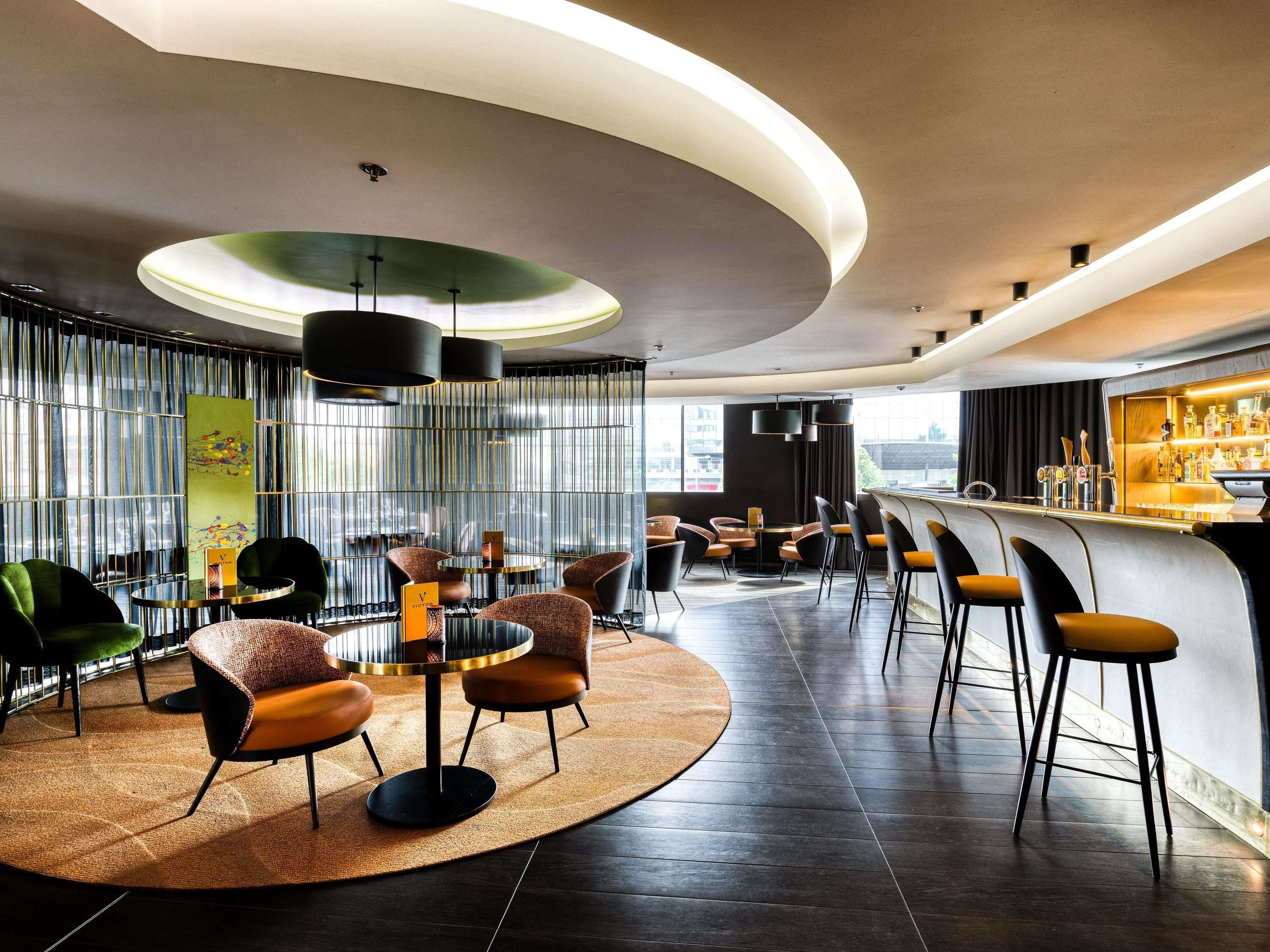 A modern bar area with round tables, bar stools, and a bar counter.