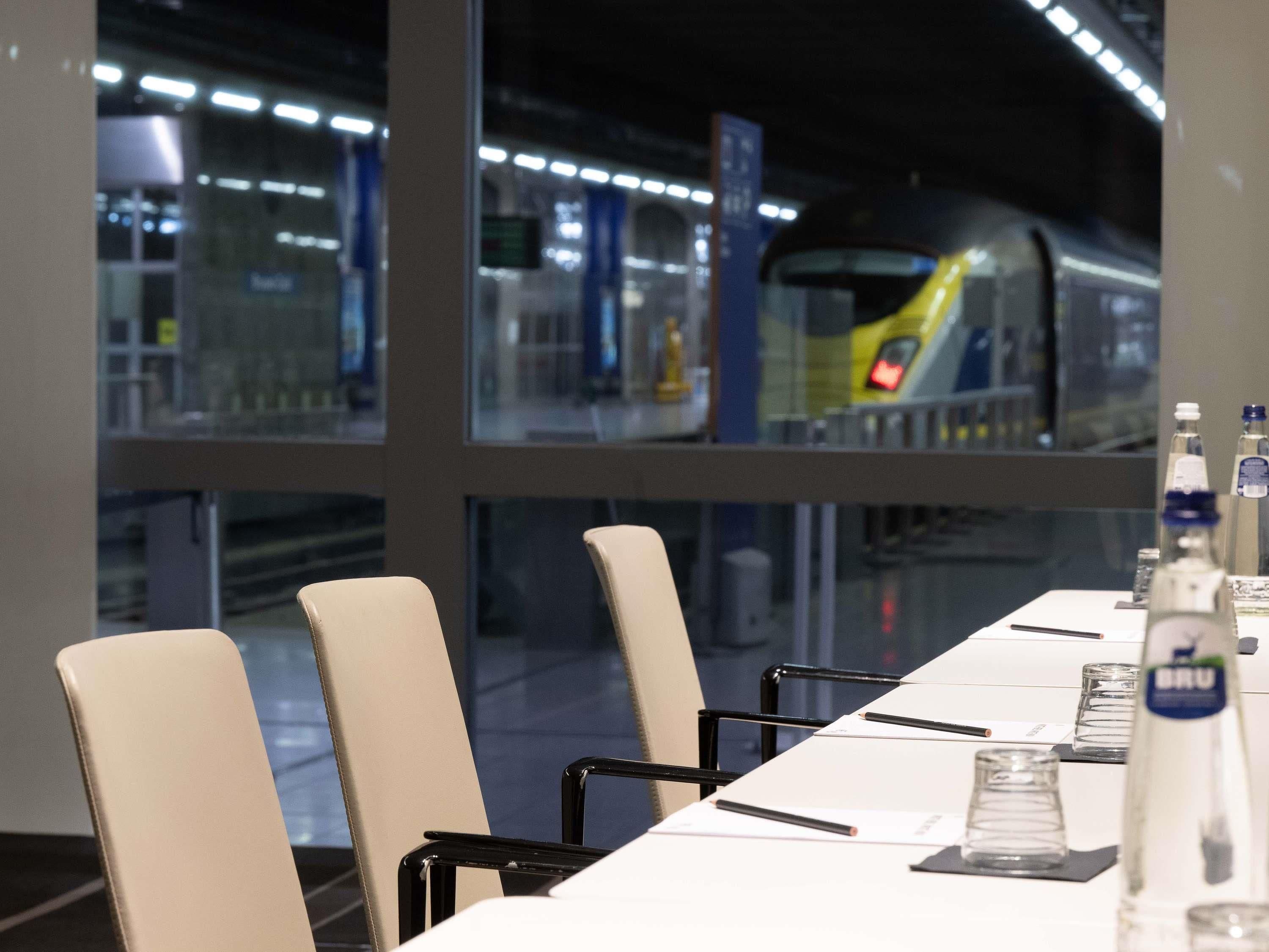 Ein Konferenzraum mit langem Tisch, Stühlen und Blick auf einen Zug.