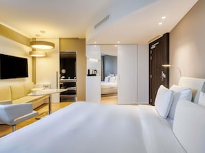 A modern hotel room with a large bed, a desk, a chair, a TV, and a wardrobe. - Pullman Brussels Centre Midi (Brussels)
