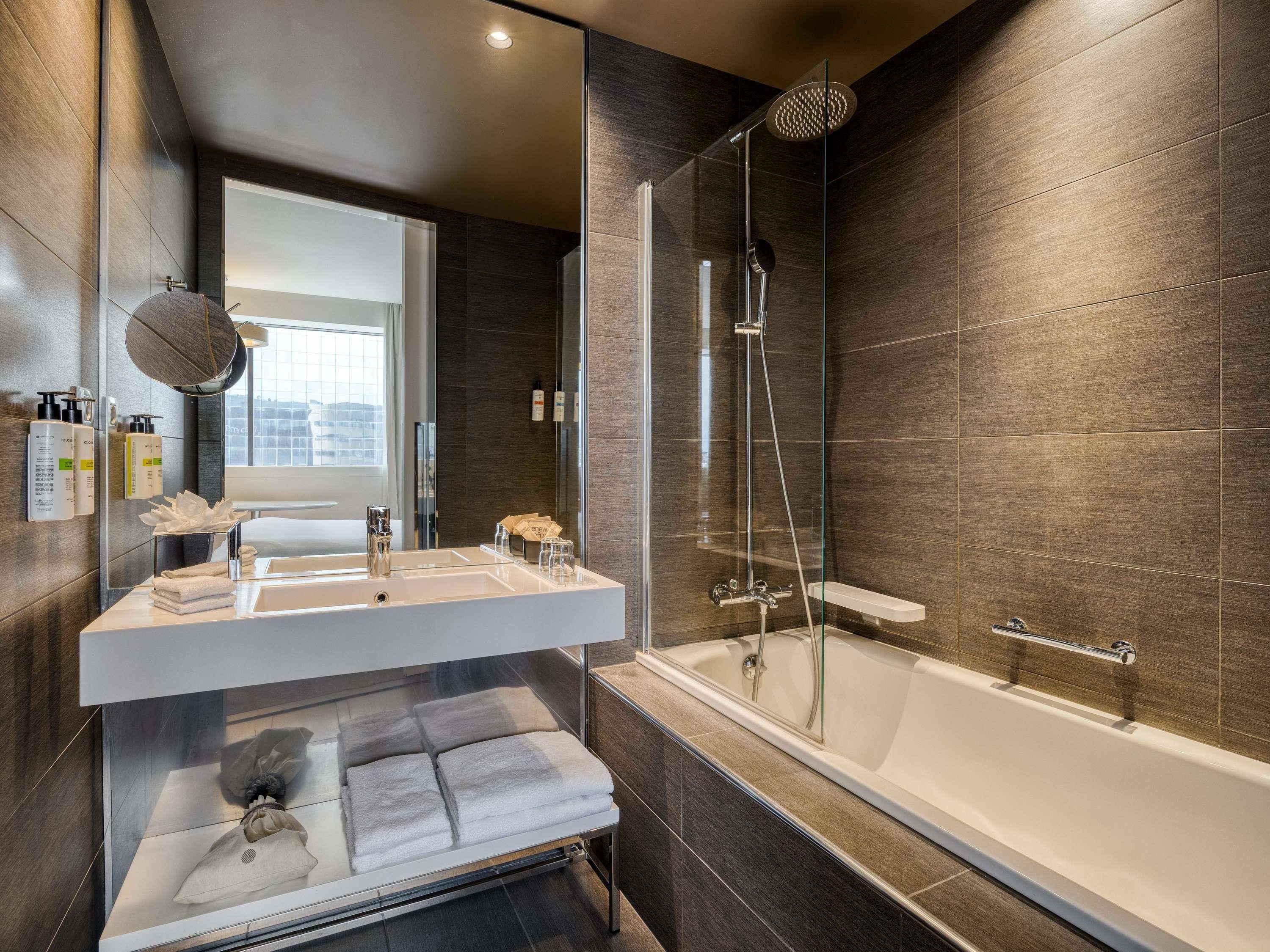 Un baño moderno con ducha acristalada, tocador con espejo y bañera.