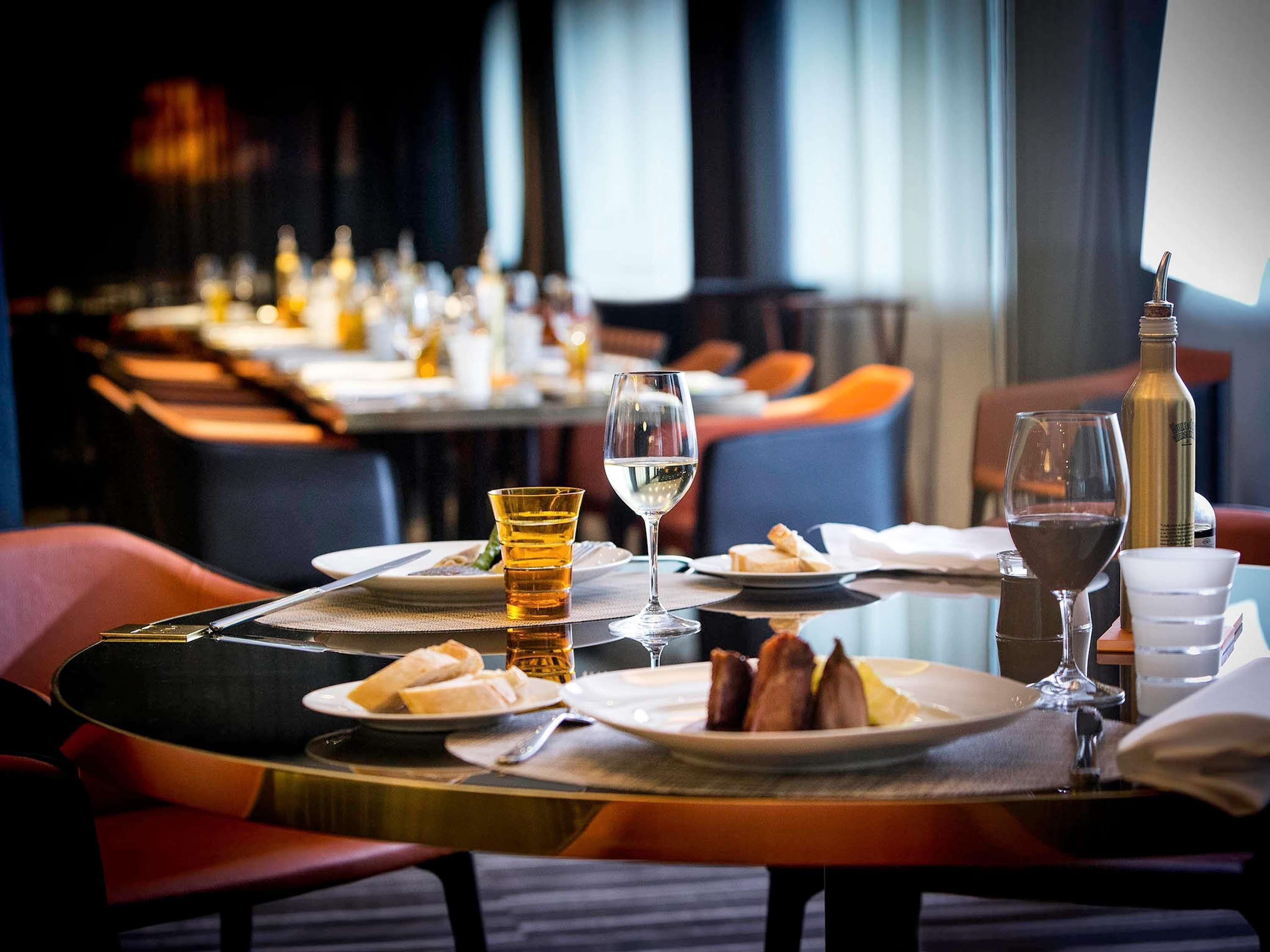 A restaurant setting with tables set for dining, glasses of wine, and a bottle on the table.