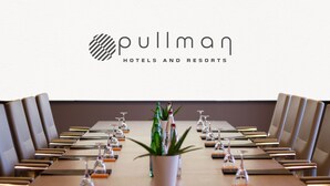 Kokoushuone, jossa on Pullman-logon näkyvillä, pitkä pöytä tuoleineen ja ruukussa oleva kasvi huoneen keskellä.