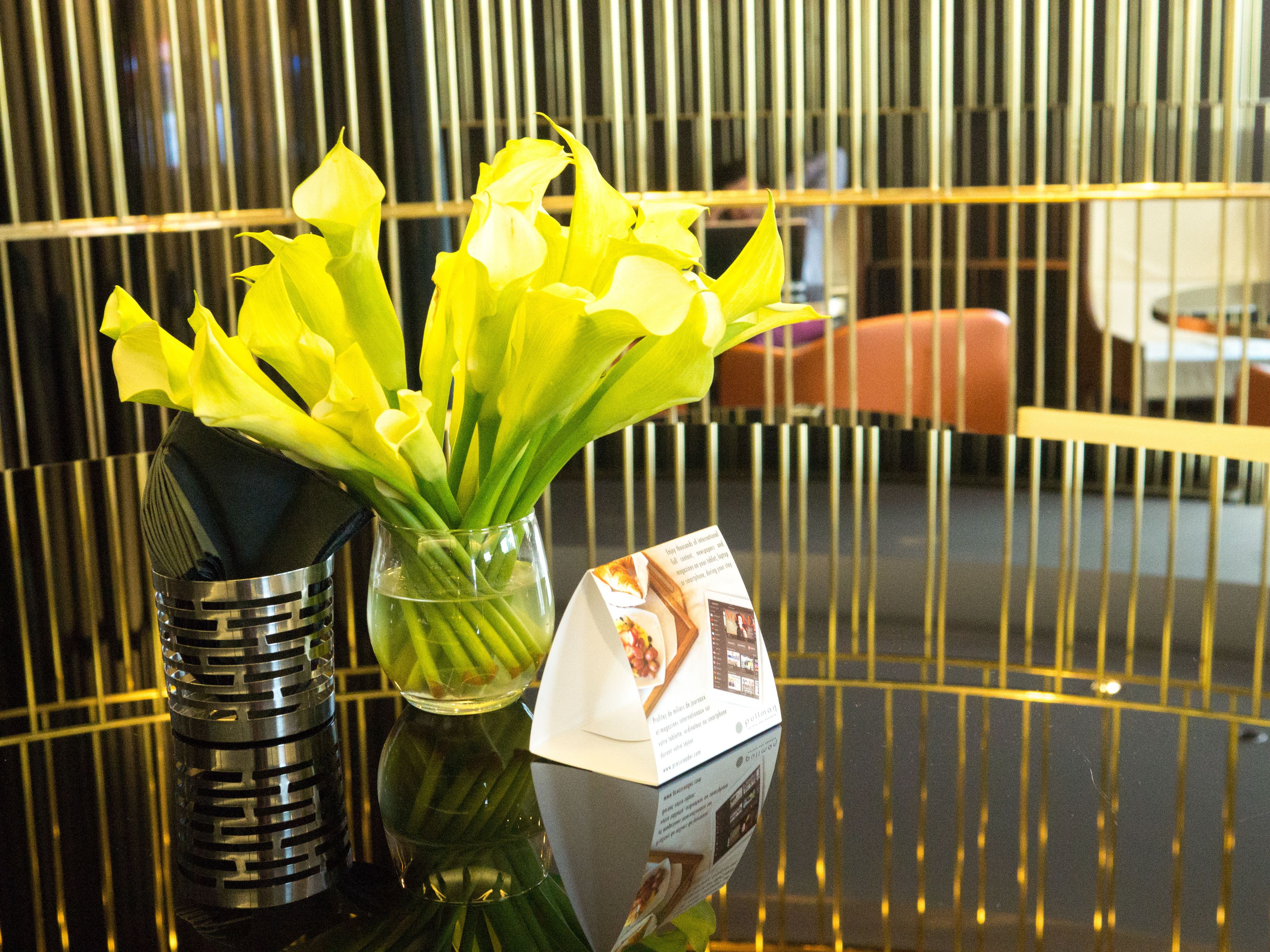 A glass vase with yellow flowers on a reflective surface.