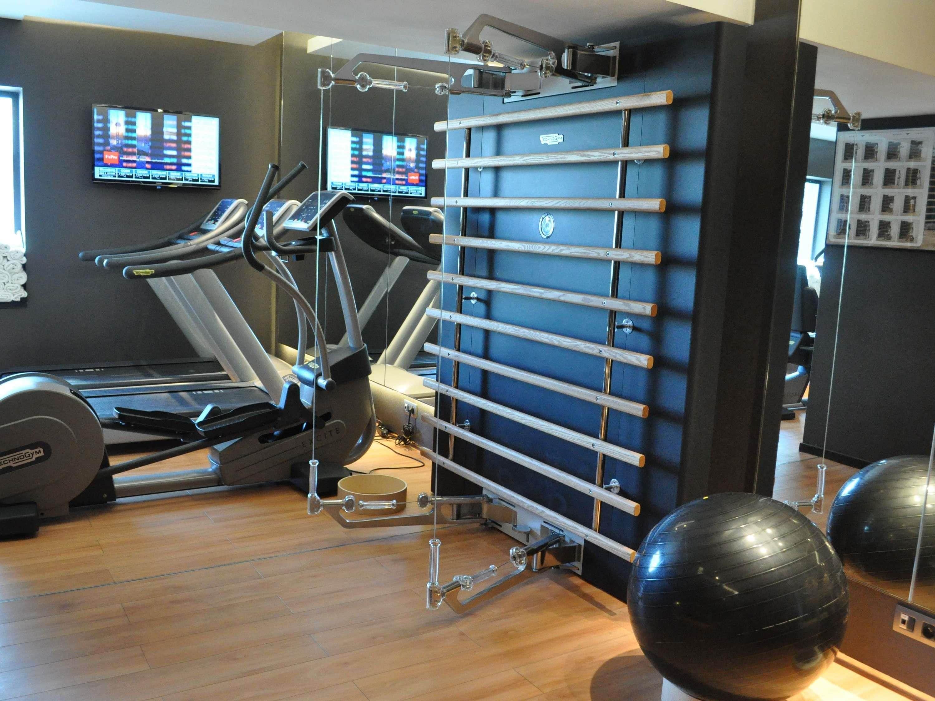 Een fitnessruimte met trainingsapparatuur, waaronder loopbanden en een wandrek.