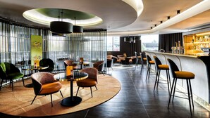 A modern bar area with round tables, bar stools, and a bar counter. - Pullman Brussels Centre Midi (Brussels)