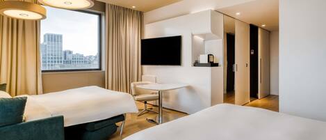 A hotel room with two beds, a desk, a chair, a TV, and a city view.