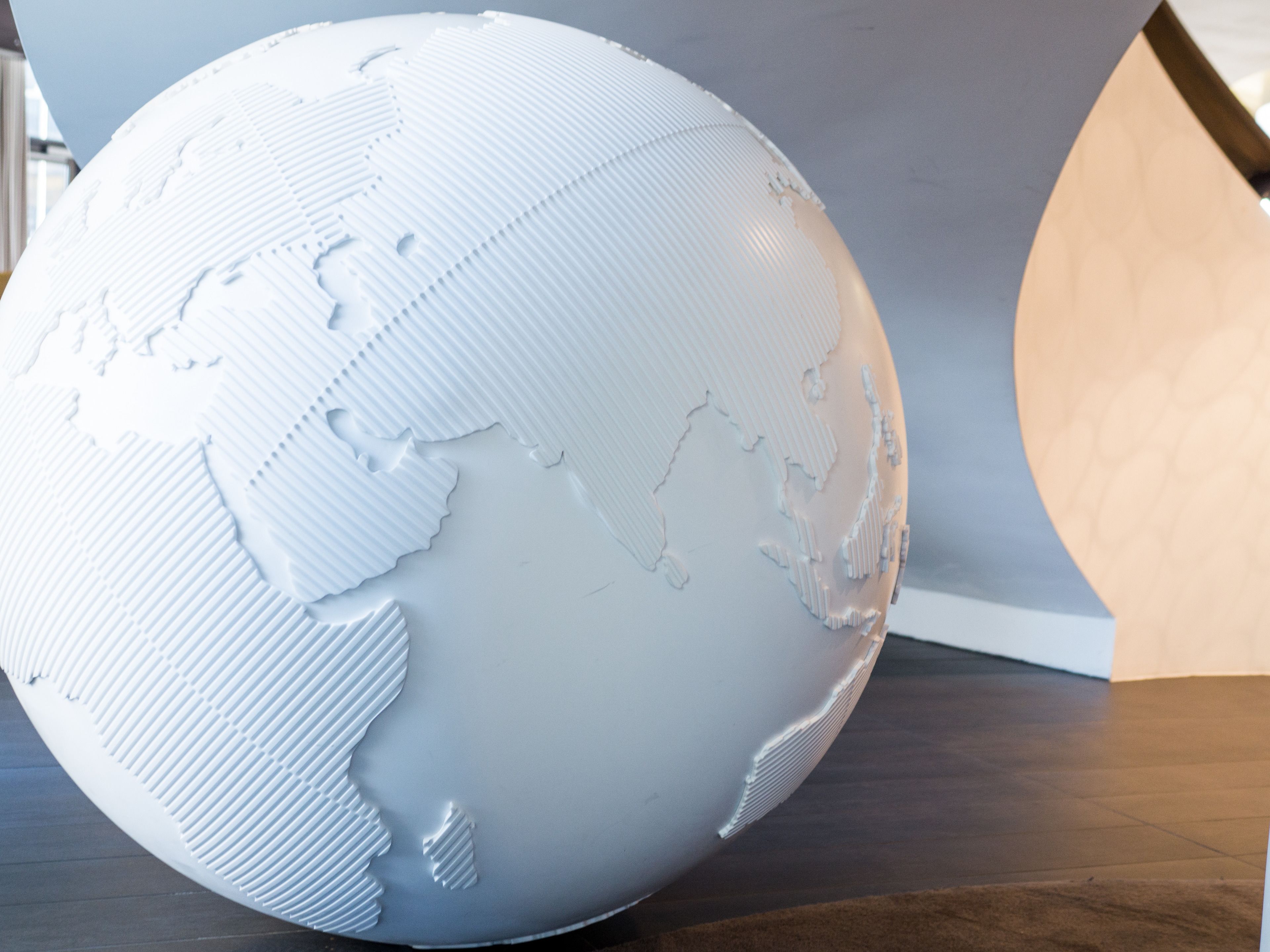 Un globo esférico con superficie texturizada, sobre un piso de madera oscura.