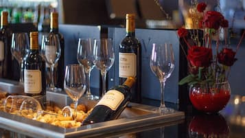 Une présentation de vins avec des bouteilles et des verres, un vase rempli de roses rouges et une bouteille de vin « Pinot Noir ».