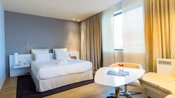 Una habitación de hotel moderna con una cama grande, mesitas de noche, un escritorio y una silla.