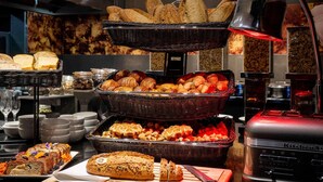 A buffet with various breads and pastries, a cutting board with a knife, and a kitchen appliance in the background. - Pullman Brussels Centre Midi (Brussels)