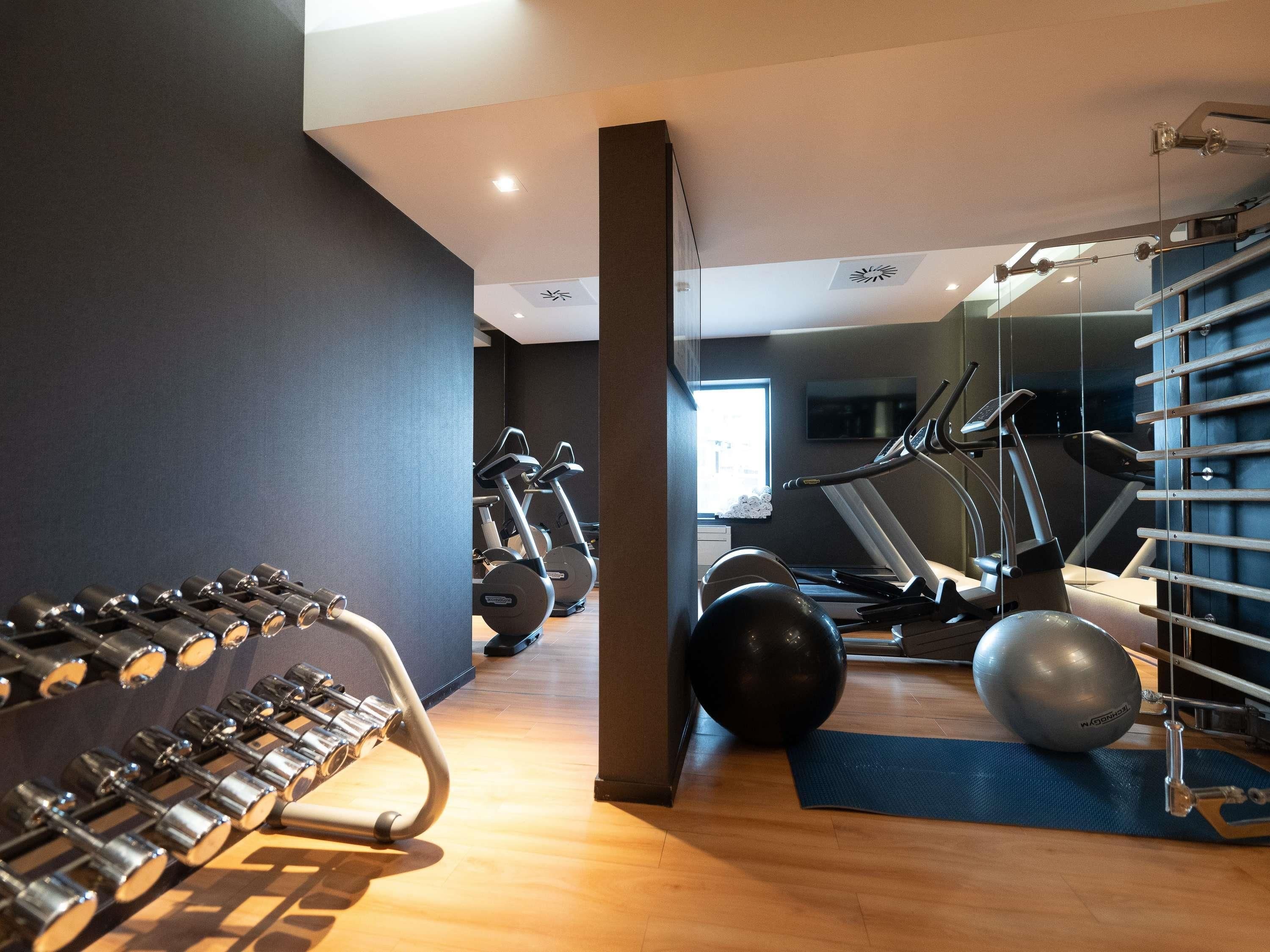 A gym with exercise equipment, a treadmill, and a mirrored wall.