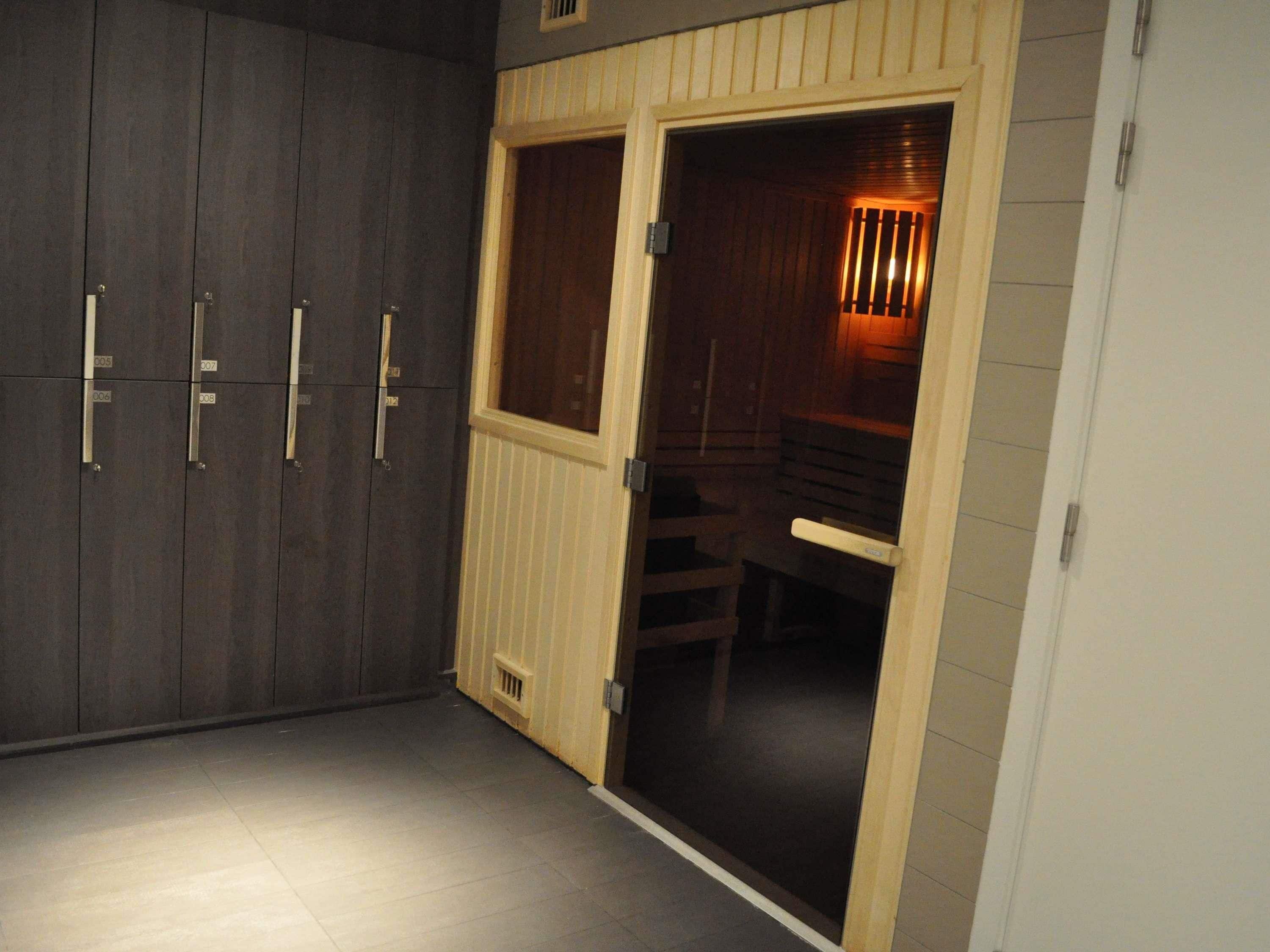 Una habitación con un armario de madera oscura, una puerta de madera que da al baño, y un banco en el baño.