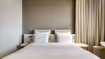 Une chambre d’hôtel avec un grand lit, deux tables de chevet, une lampe de chevet et un rideau.