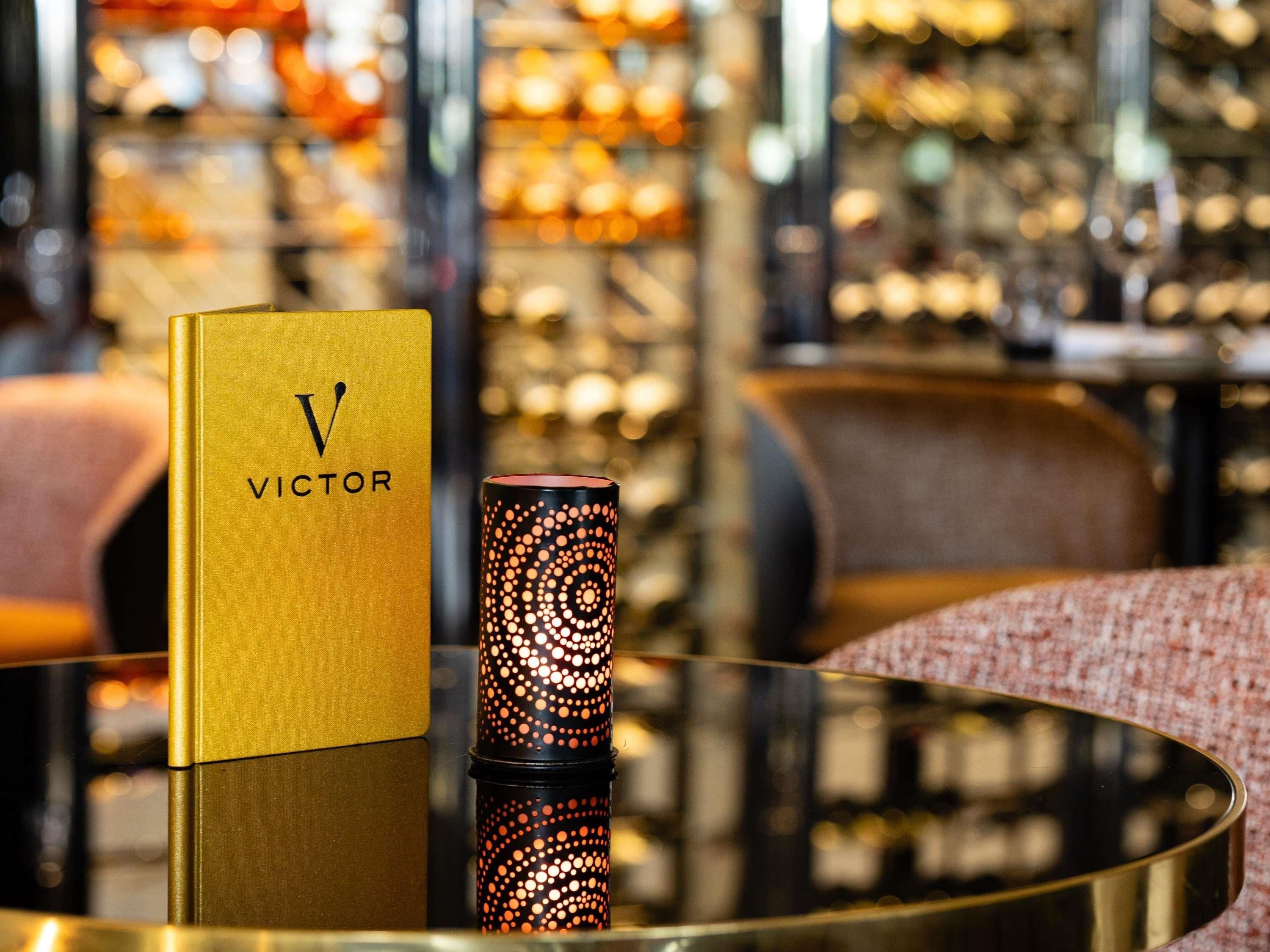 A gold-colored box with 'VICTOR' on it, a cylindrical object with a patterned design, and a reflective surface.