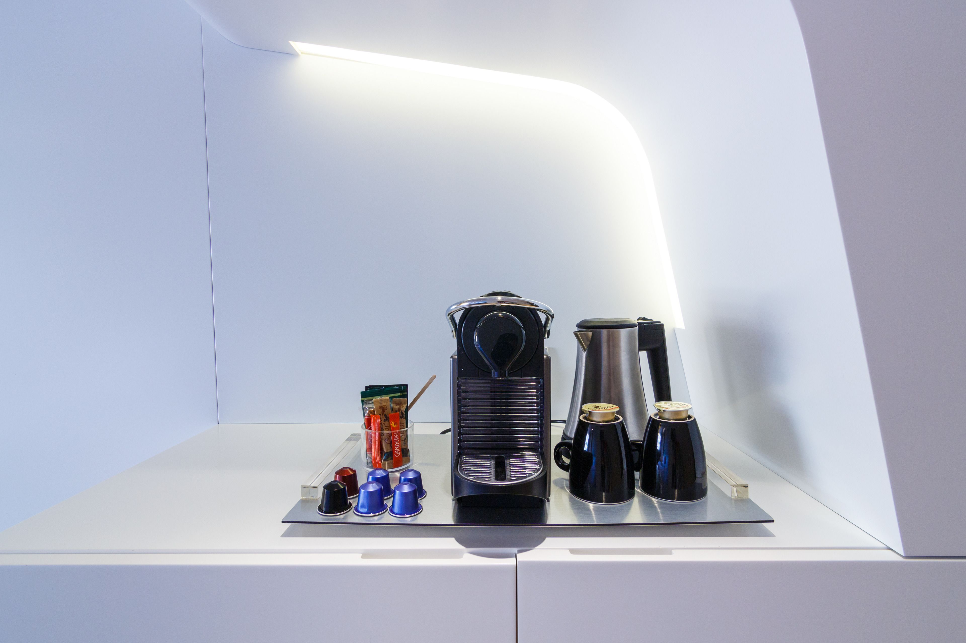 Een koffiehoek met een koffiezetapparaat, kopjes en een waterkoker.