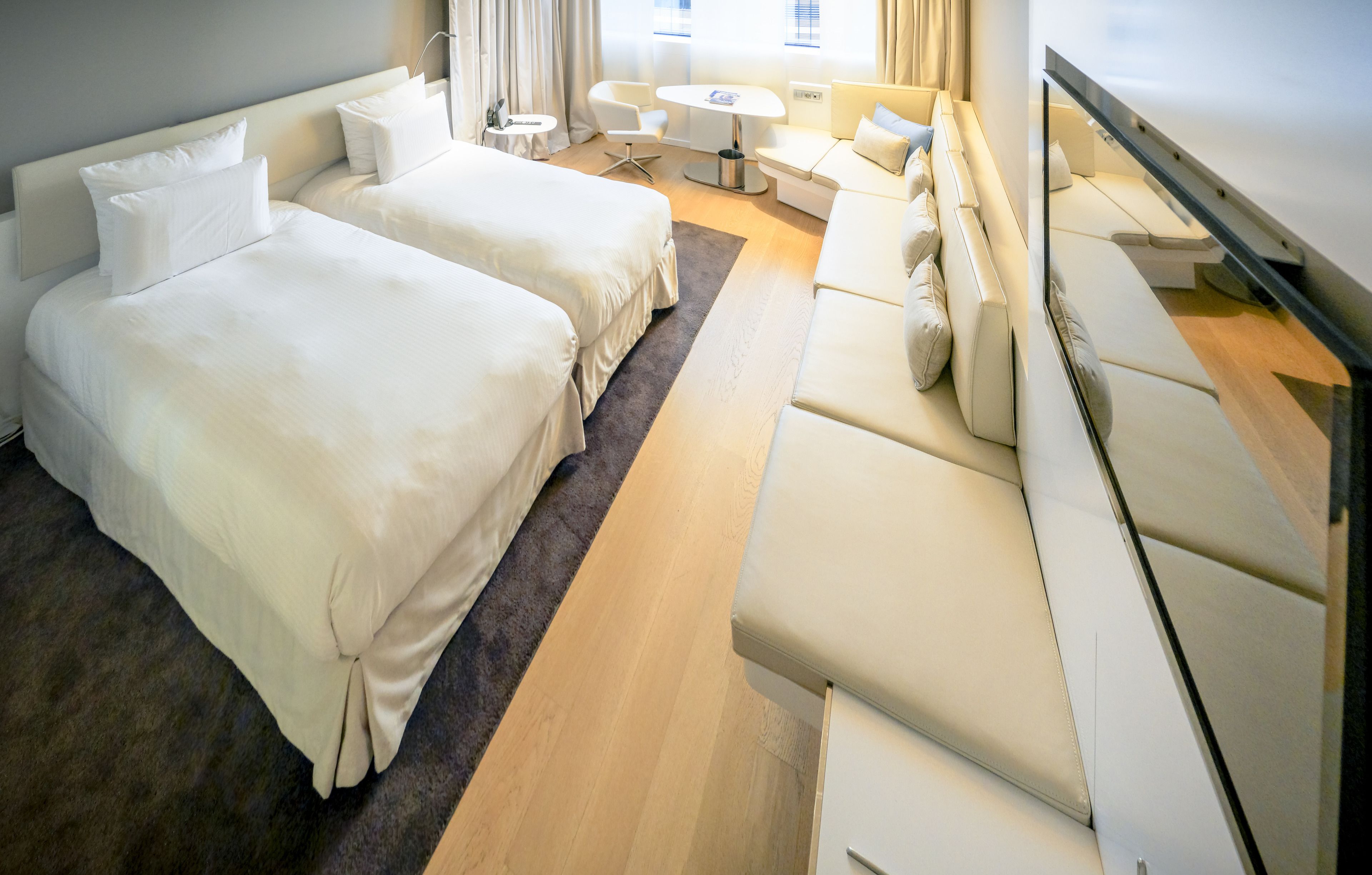 Habitación de hotel con dos camas, un sofá, una mesita y un televisor.