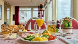 A breakfast setting with a variety of foods, including eggs, vegetables, and bread, along with beverages and condiments. - FF&E Hotel Dania (Fehmarn)