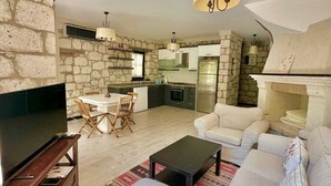 A modern living room with a large TV, a sofa, and a dining area with a table and chairs. - Imren Han Hotel - Special Class (Cesme)
