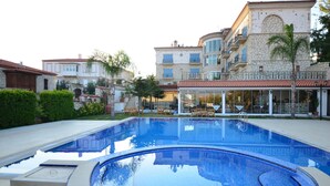 A swimming pool with a clear blue water surface, surrounded by stone buildings with balconies and windows. - Imren Han Hotel - Special Class (Cesme)