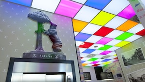 A hotel reception area with a colorful ceiling and a statue of a tree. - Jc Rooms Santo Domingo (Madrid)