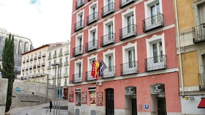 A multi-story building with balconies, a restaurant sign, and flags. - Jc Rooms Santo Domingo (Madrid)