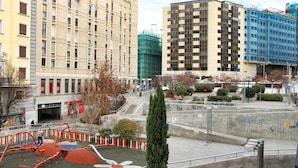 A playground with a flower design, surrounded by buildings and a staircase. - Jc Rooms Santo Domingo (Madrid)