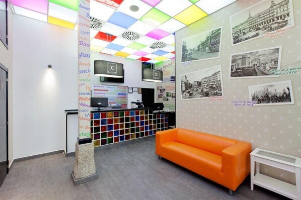 Zona de recepción con un techo llamativo, mostrador de recepción y una pared con fotografías históricas.