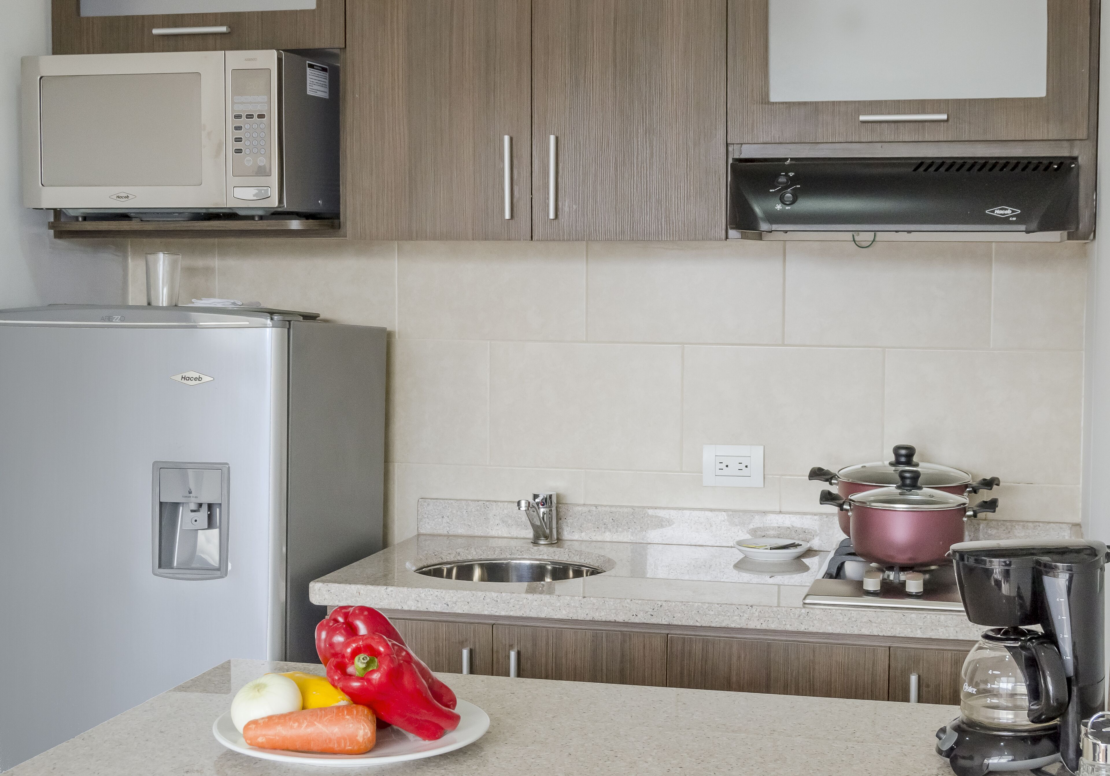 Una cocina con microondas, estufa, fregadero y un plato de verduras.