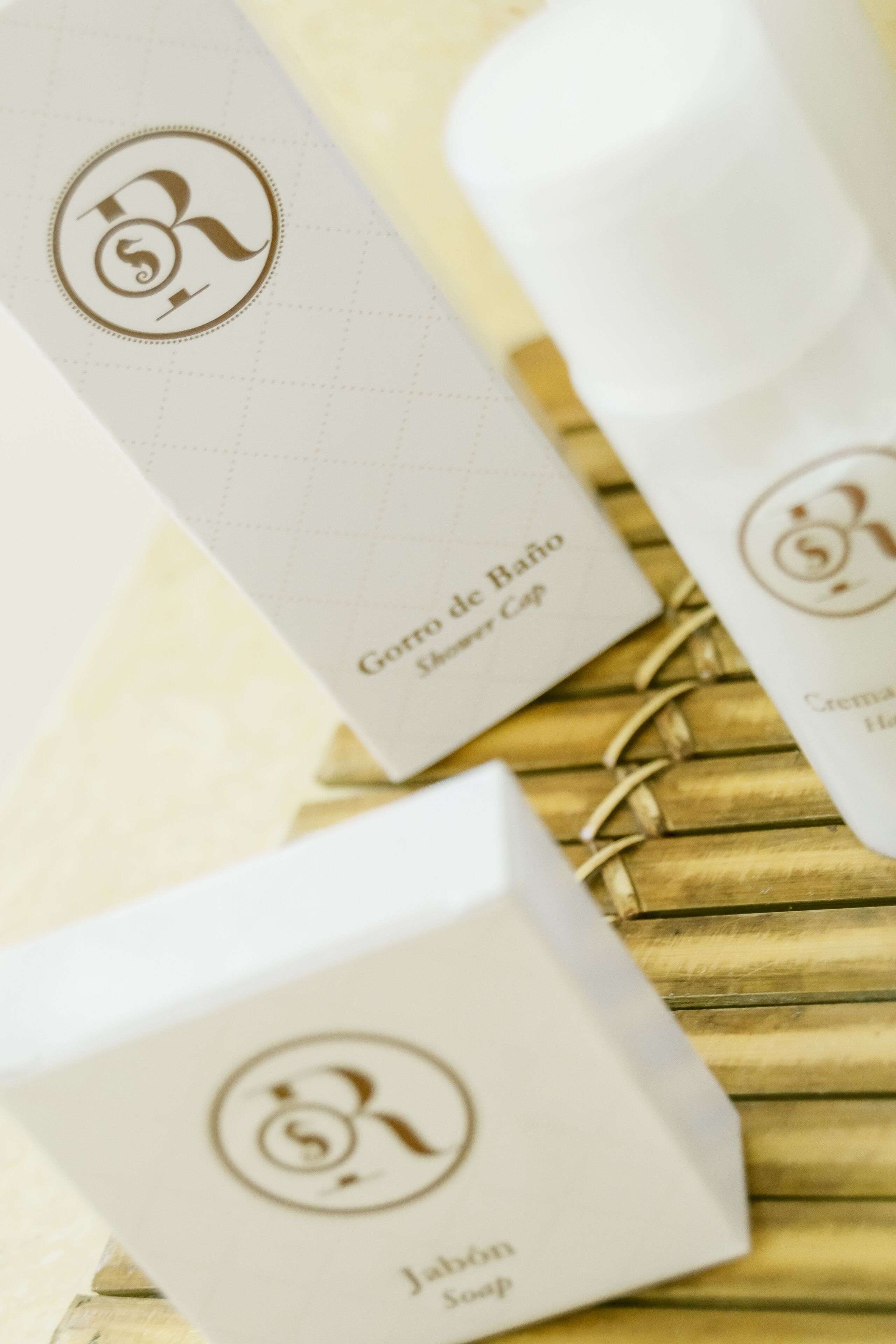 Tres cajas blancas con logotipos y texto en relieve, sobre una superficie de madera.