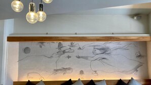 A modern interior with a wall mural, a wooden bench with cushions, and pendant lighting. - Santiago Guesthouse Kyoto (Kyoto)