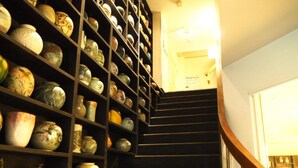A staircase with shelves on either side holding various ceramic items. - Santiago Guesthouse Kyoto (Kyoto)